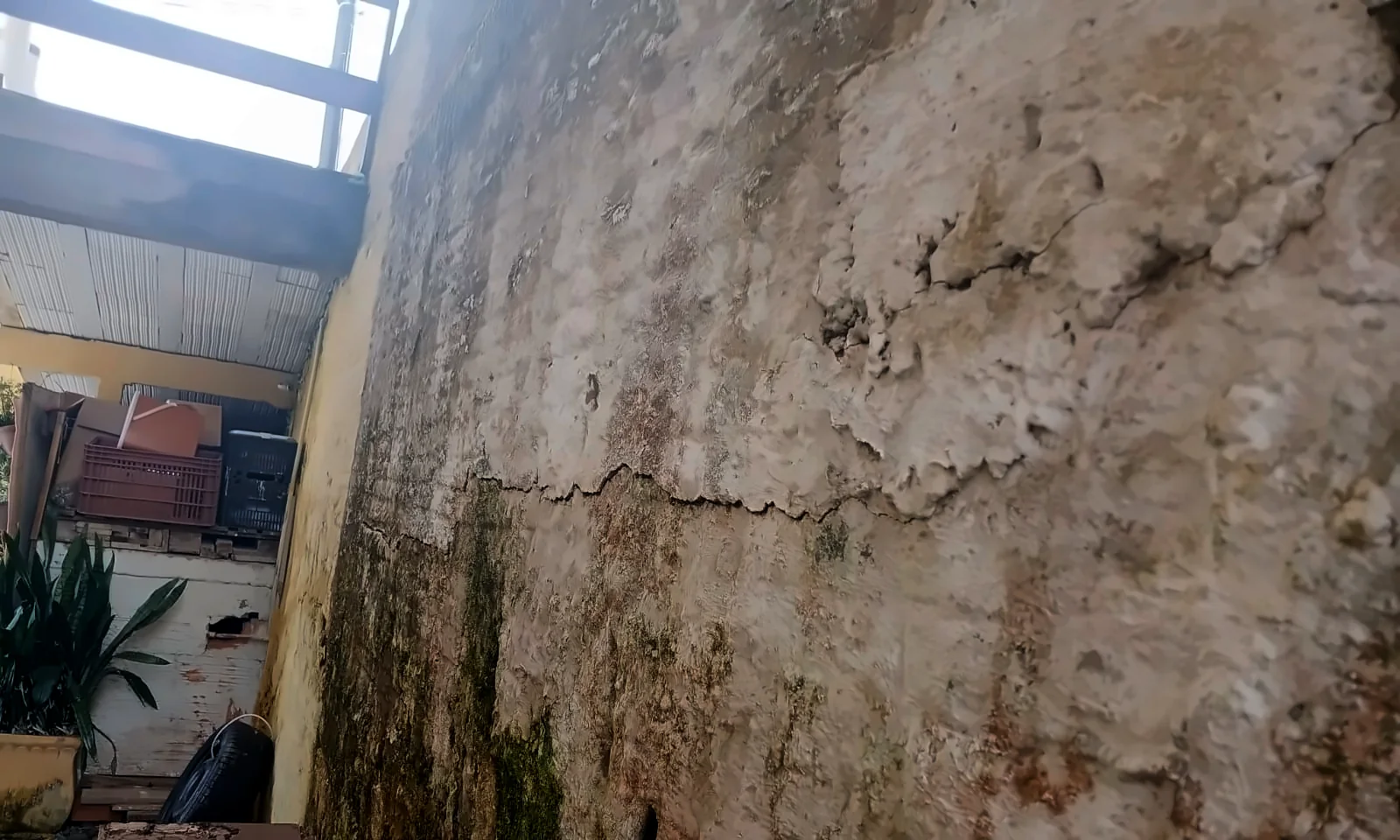 Fissura e manchas de umidade em um muro. Foto real de vistoria