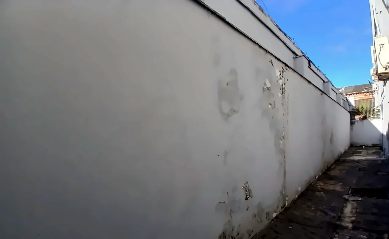 Muro com pintura descascando por umidade. Foto real de vistoria